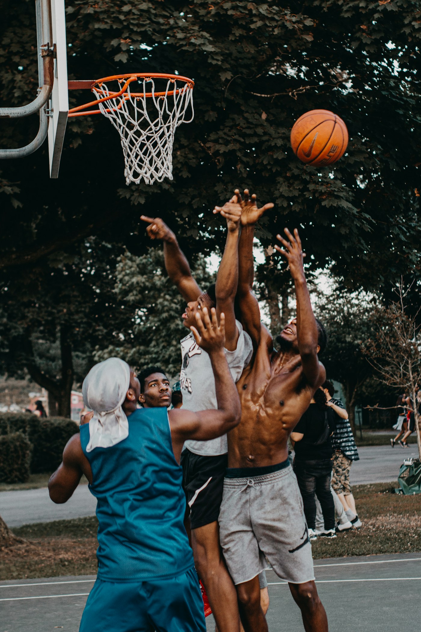 Players reaching for the ball in an outdoor basketball game.