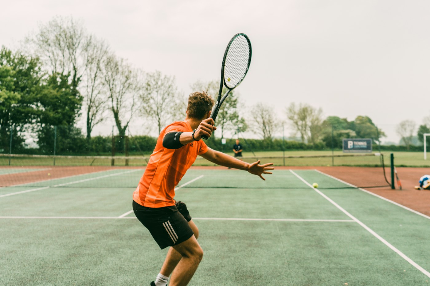 A tennis player reaching for a shot on an outdoor court.